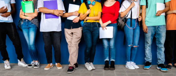 Horizontal banner image of group of multiracial teenage high school students ready to go back to school standing against blue background wall. Education concept.